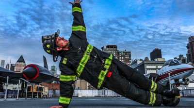 Photo of a fire responder in fully uniform practicing yoga and holding side plank pose.